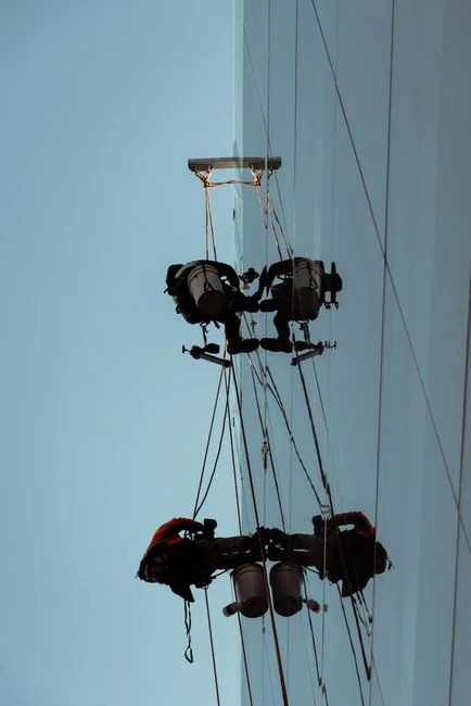A man cleaning skyscraper windows with a harness, showcasing urban high-rise work.